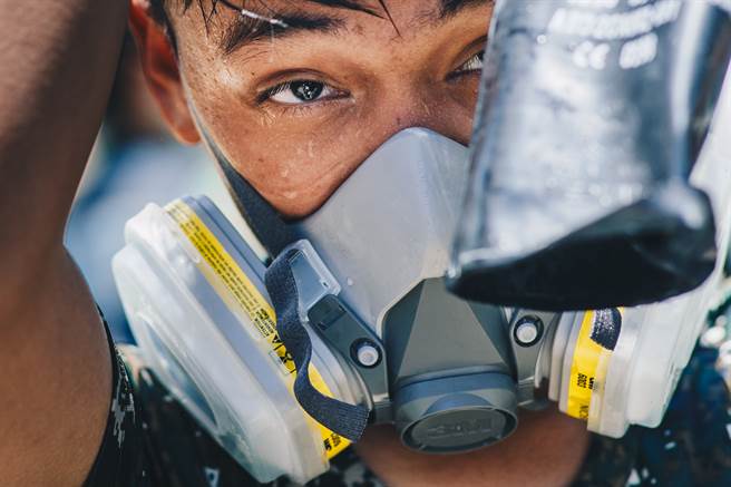 官兵不畏天气炎热，逐一完成消毒作业，脱掉防护服后，可看见大量汗水。（军闻社提供）