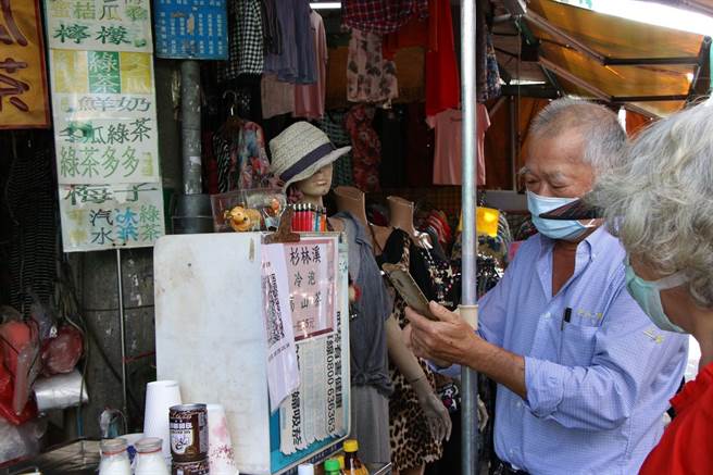 嘉义市共和市场摊商教买菜的长辈扫瞄手机实联制。（嘉义市政府提供）