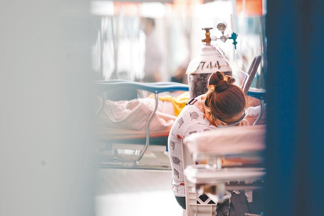 台灣本土新冠肺炎疫情持續延燒，聯合醫院忠孝院區屢傳出病床不足、醫護人力又投入快篩，幾乎壓垮醫護能量，一位急診病患與其家屬只能在院外棚區等待。（郭吉銓攝）