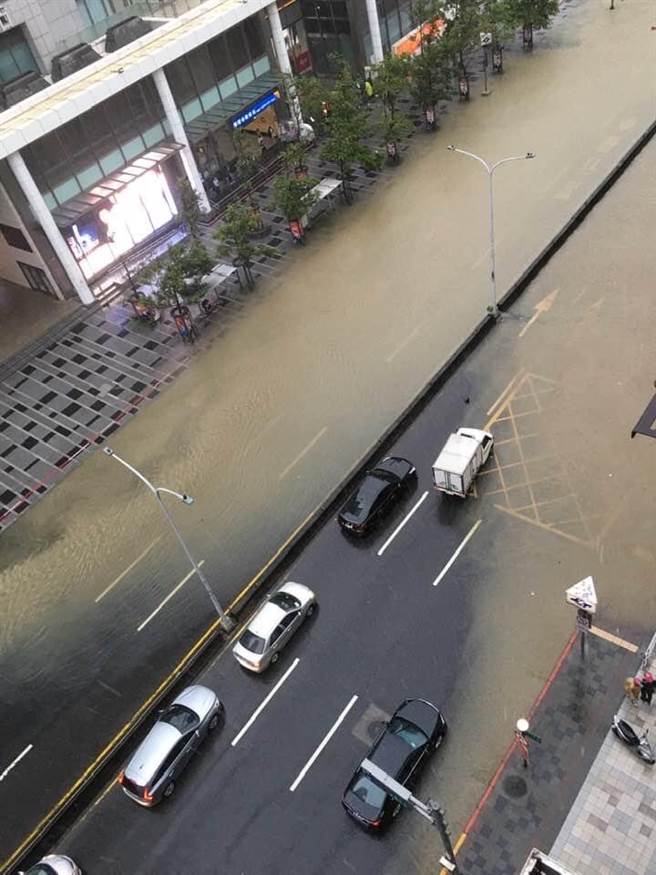 今（4）日信義區午後瞬間暴雨，馬路驚現「水舞秀」，水溝一秒變噴泉蓋過機車。（圖／熱心民眾提供）