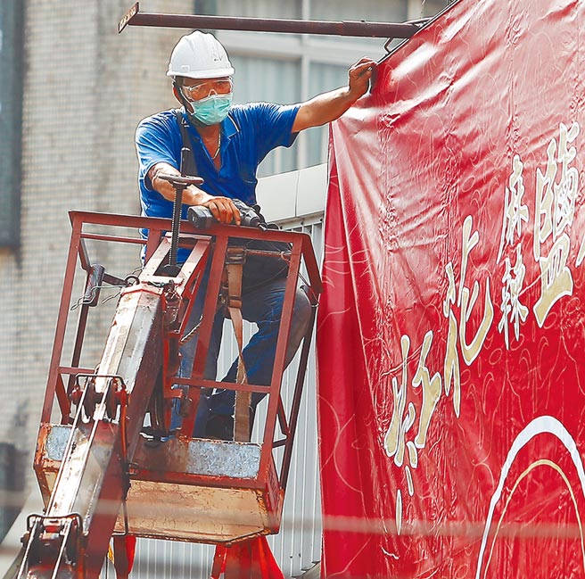 行政院会3日通过纾困4.0预算，民团喊话政府，对受衝击的营业、住宅租屋者提供紧急的租金补贴；并禁止房东对因疫情而缴不出房租者下达驱逐令。图为搭乘吊车架设广告帆布的劳工。（季志翔摄）