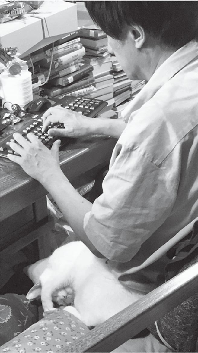 在家中客厅餐桌工作写书的爸爸背影与爱猫BuBu。（时报出版提供）