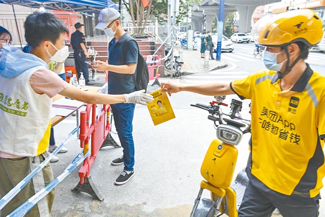 大陸廣東疫情嚴峻，這一輪截至6月3日累計本土確診71例，變異株病毒首次在大陸社區內傳播。圖為實施小區封閉，配送員將貨物交給小區工作人員。（中新社）