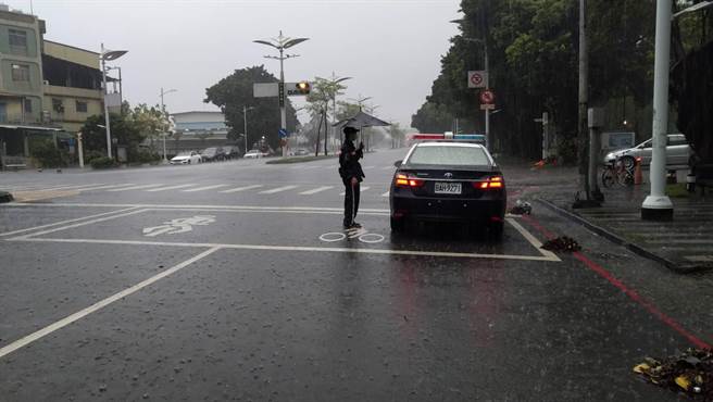 小港暖警在雨中徒手清理排水孔，使淹水问题得以解决，也还予民眾安全无虞的道路。（警方提供）