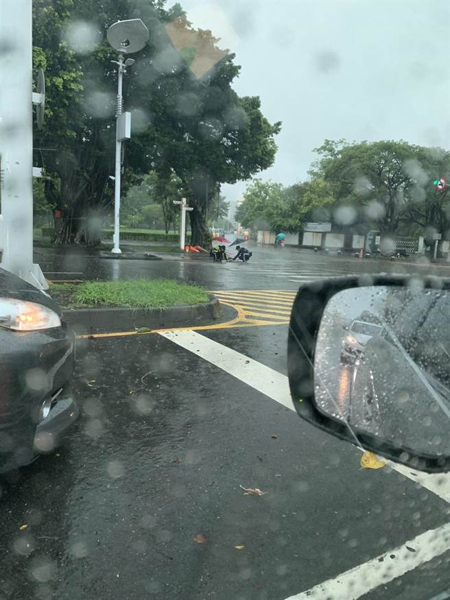 小港暖警在雨中徒手清理排水孔，使淹水问题得以解决，也还予民眾安全无虞的道路。（警方提供）