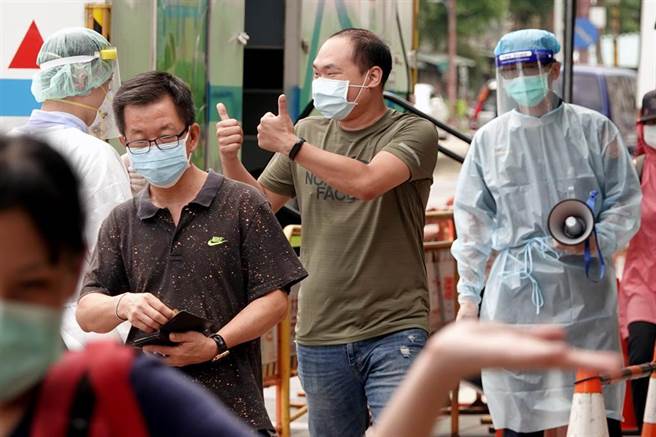 1位民眾得知快篩結果為陰性後，開心地向一旁的工作人員比出大拇指加油打氣。（黃世麒攝）
