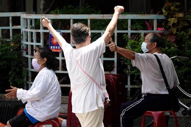 1位民眾（中）得知快篩結果為陰性，興奮地高舉雙手歡呼，一旁的民眾也對她比出大拇指回應。（黃世麒攝）

