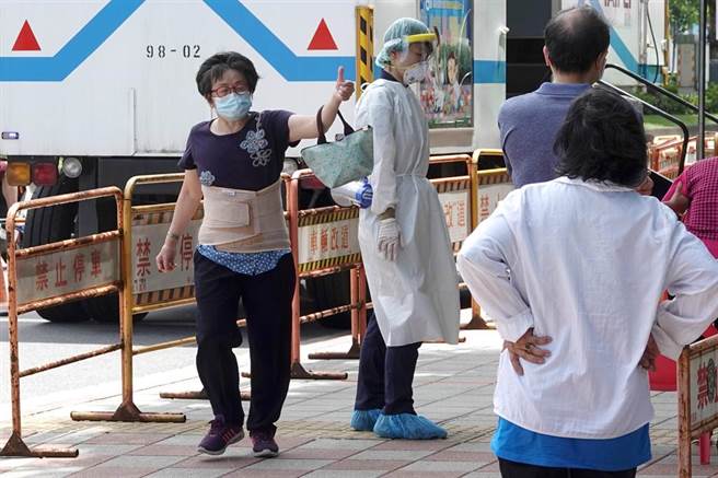 1位民眾（左）得知快筛结果为阴性，离去时开心地比出大拇指，为在场的工作人员加油打气。（黄世麒摄）

