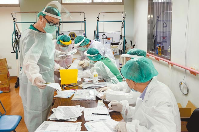 多位新北联医三重院区工作人员正在制作民眾快筛的检疫包，里面包括个人专属条码、採检棒、申请表、健保卡等，由于参与新冠肺炎抗原及核酸检测人数眾多，院方必须动员大量人力增加检验能量。（黄子明摄）