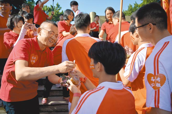 大陸2021年高考（大學入學考試）於7日正式開始，今年共有1078萬名考生參加這項考試，大部分省市都明確要求，考生須提前14天，也就是從5月24日起實行考前連續14天健康監測。圖為廣西南寧一名教師為高三學子派發粽子和糕點並送上祝福。（中新社）