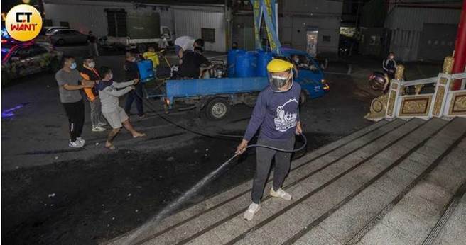 消毒团员手持喷洒器，后方则有人员负责拉管线，团队分工合作，经过时庙宇还会特意入内加强消毒。（图／宋岱融摄）