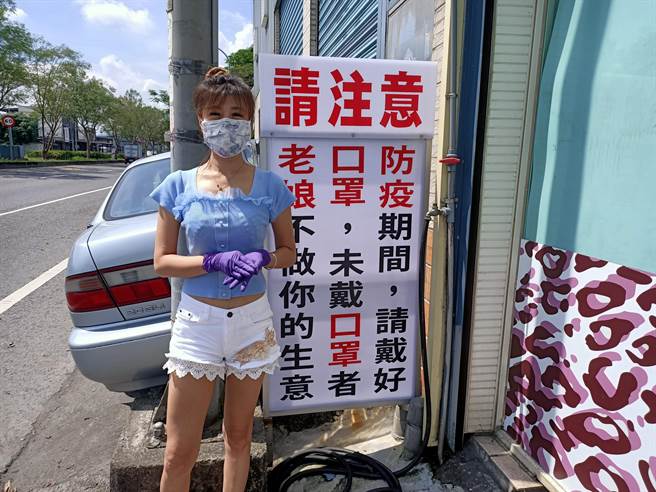 槟榔摊老板娘黄小姐站在她霸气的「防疫看板」旁，坚守她「不戴口罩、不做生意」 的原则。（胡健森摄）