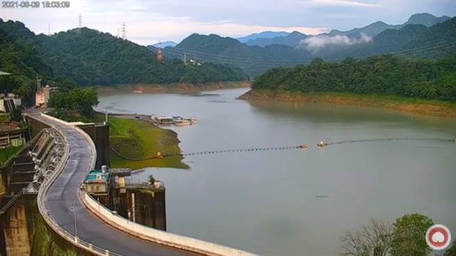 根據石門水庫即時影像，原本水壩旁露出的一大截陸地，如今已被淹到只剩一小片綠地。(圖截自桃園智慧旅遊雲 Taoyuan Travel / YouTube)