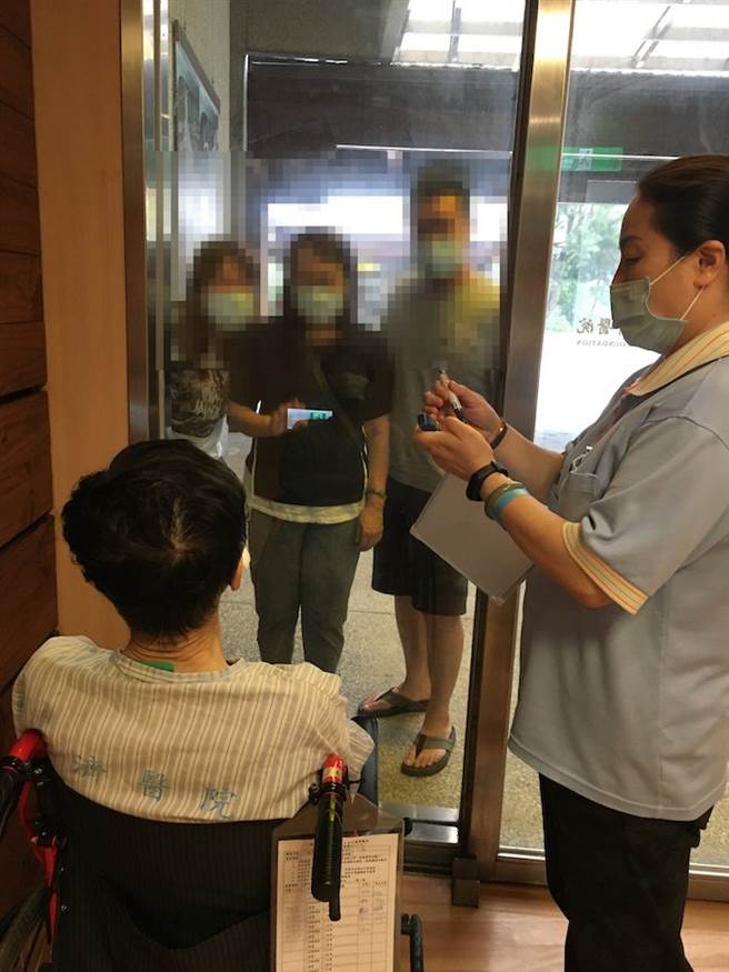 病人与家人隔着落地窗见面，用手机扩音讲讲话。（图／台中慈济医院心莲病房提供）