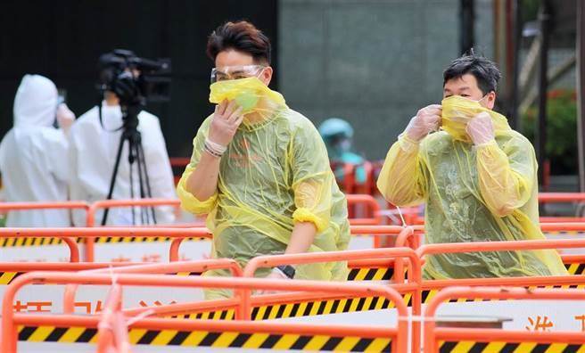 一名壹電視攝影員工日前猝死於電視台，被確診生前得到新冠肺炎，北市府快篩機動隊9日進駐該大樓篩檢，快篩陰性的員工身穿雨衣快步離開。（張鎧乙攝）
