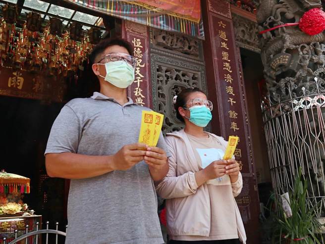 明天是端午节，民眾拿着五毒符虔诚地拜拜祈福。（张毓翎摄）