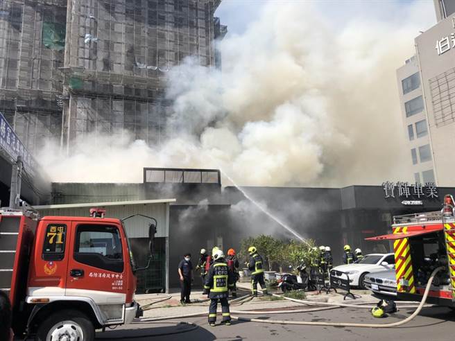 台中市西屯区福星西路一栋铁皮屋，今天下午发生火警，铁皮屋隔壁紧邻车行，消防人员利用水线防止火势蔓延。（民眾提供）