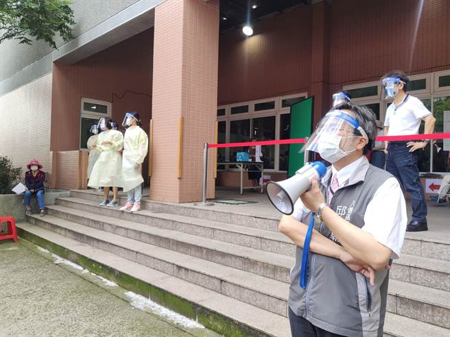 桃園八德大忠國小湧入人潮比預估稍多，區長邱瑞朝（右一）也拿大聲公引導長者報到。（賴佑維攝）