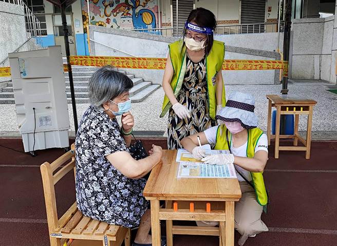 台中市15日起開放85歲以上長輩，施打AZ新冠肺炎疫苗，其中塗城國小快打站，穿著黃背心的老師，協助長者填資料。（塗城國小提供／黃國峰台中傳真）