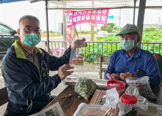 農業局長謝耀清（左）推薦消費者選購蓮子時，選擇使用印有「白河在地蓮子」字樣的公版蓮子包裝袋之業者。（台南市府農業局提供／張毓翎台南傳真）