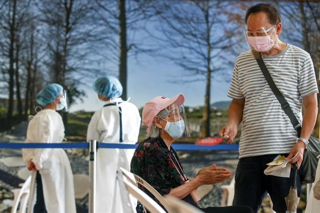 日本贈台AZ疫苗第三天開打，許多長者17日在家人陪同下前往慈濟接種站施打疫苗，一位等候施打的長者雙手合十靜靜等待，家人則於一旁，幫老人家搧風消暑。（鄧博仁攝）
