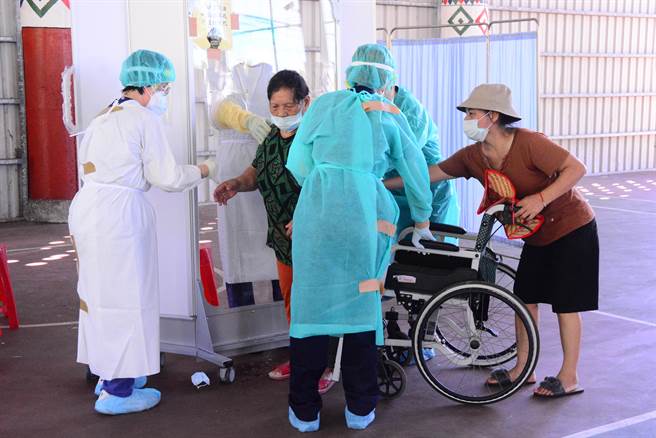 坐轮椅长辈，在旁人搀扶接受快筛。（王志伟摄）