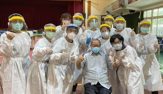 102岁耳聪目明的阿公来施打疫苗，身体硬朗，医护团队穿着隔离衣跟他照相，祝福彰化县的每位长者，都如此健康快乐。（彰化县卫生局提供／吴敏菁彰化传真）