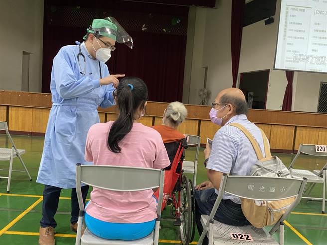 南区庆耀联合诊所小儿科医师林恒圭负责国光国小快打站医务，他细心回答长者家属，接种完疫苗后注意事项。（冯惠宜摄）