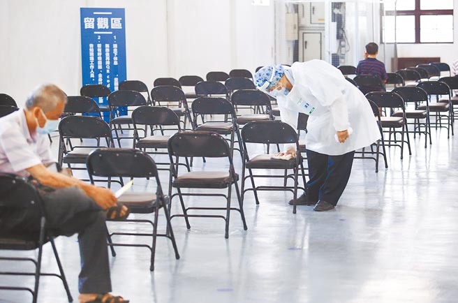 国泰医院17日在松菸文创园区5号仓库为民眾接种疫苗，施打人数已比起前二天减少许多，场地动线规划得宜，採取分流措施，民眾在舒适环境中施打疫苗，图为清洁人员喷酒精擦拭椅子。(陈俊吉摄)