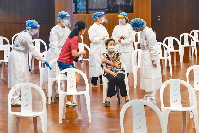 台湾自15日大规模接种AZ疫苗以来，累计通报11例死亡，疫情指挥中心呼吁民眾在未厘清因果关系前，不要却步不打疫苗。图为一名长者17日前往双和静思堂接种站施打疫苗，适逢人流较少时刻，留观区医护在长者及家属旁关切身体状况。（黄子明摄）
