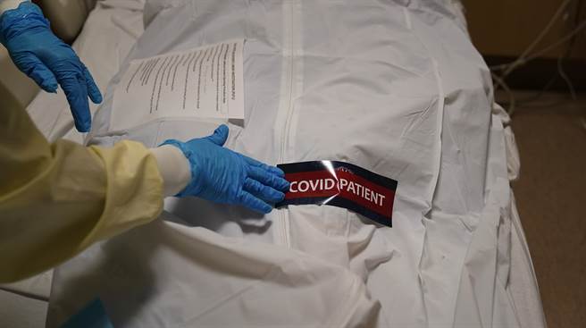 新冠肺炎肆虐至今，美国已有超过60万人死亡，图为南加州洛杉矶普罗维登斯圣十字医学中心（Providence Holy Cross Medical Center）的工作人员在尸袋贴上「新冠病患」标籤。（美联社）