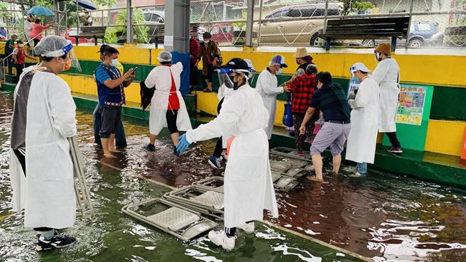 高雄市那玛夏区21日上午为长辈施打疫苗，突然碰到一场大雨，工作人员以椅子垫在地上，供长辈行走。（高雄原民会提供／林瑞益高雄传真）