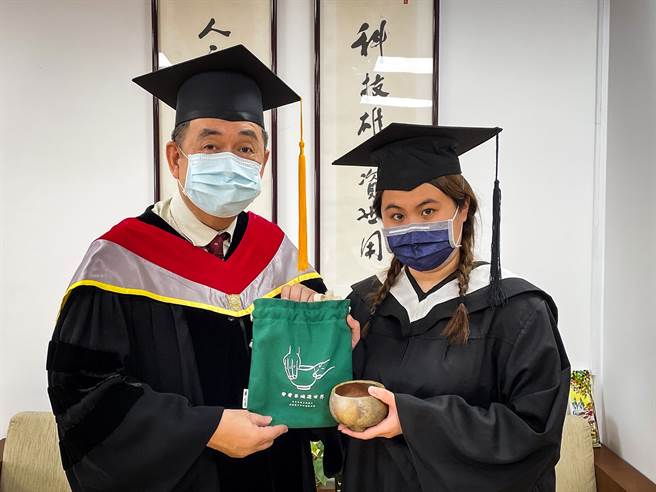 華梵大學今年於學期中邀請每位畢業生，親手捏塑屬於自我風格的茶碗，再放入校園內的「華梵窯」柴燒，製成千變萬化自然釉彩與豐富視覺效果的茶碗，每一件都獨一無二。華梵大學校長李天任（左）致贈畢業生代表茶碗。（圖/華梵大學提供）