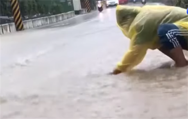 民眾試圖清除路面上水孔蓋髒物，好讓積水快速宣洩。（圖／翻攝自YouTube畫面） 