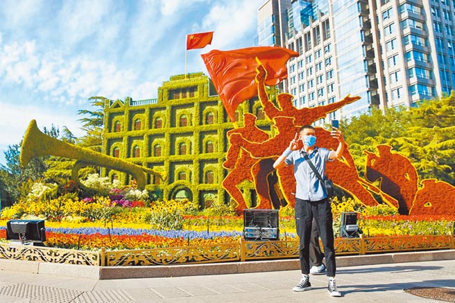 中共建党百年活动倒数，北京的安检措施升级。图为北京市民在主题花坛前自拍。（中新社）