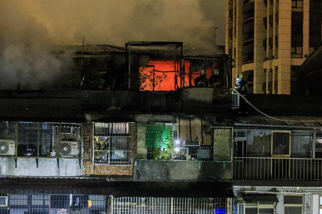 由于5楼加盖火势猛烈，消防人员需在屋檐上小心翼翼行走才得以靠近火场。（杜宜谙摄）