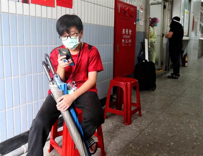 一位小朋友陪着妈妈到注射站外等候妈妈打完针，同时也获得在疫情三级警戒下短暂外出放风的机会，。（郑任南摄）
