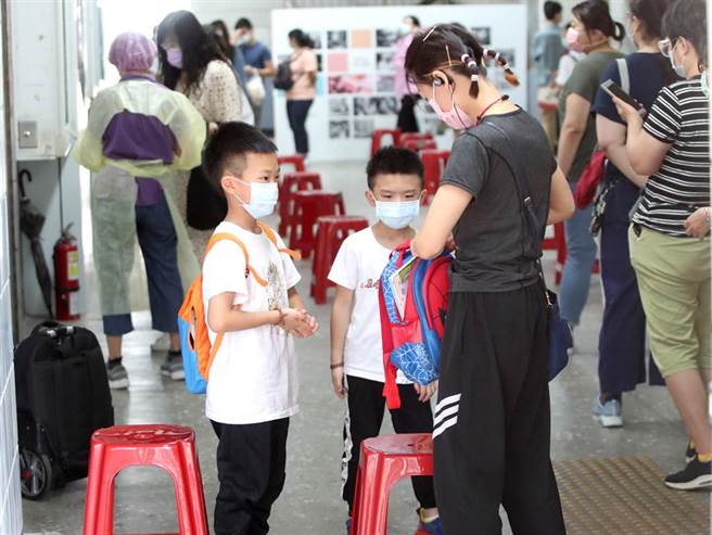 两位小朋友陪着妈妈到注射站外等候妈妈打完针，同时也获得在疫情三级警戒下短暂外出放风的机会。（郑任南摄）
