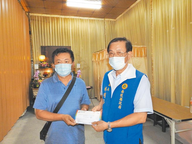 南投县长林明溱（右），致赠施打疫苗死亡者家属慰问金。（南投县政府提供／廖志晃南投传真）