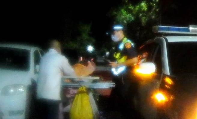 員警見當時天空開始飄雨，立即遞上全新乾淨的口罩給老翁，並快速幫忙老翁將撿拾物品捆綁固定。（警方提供）