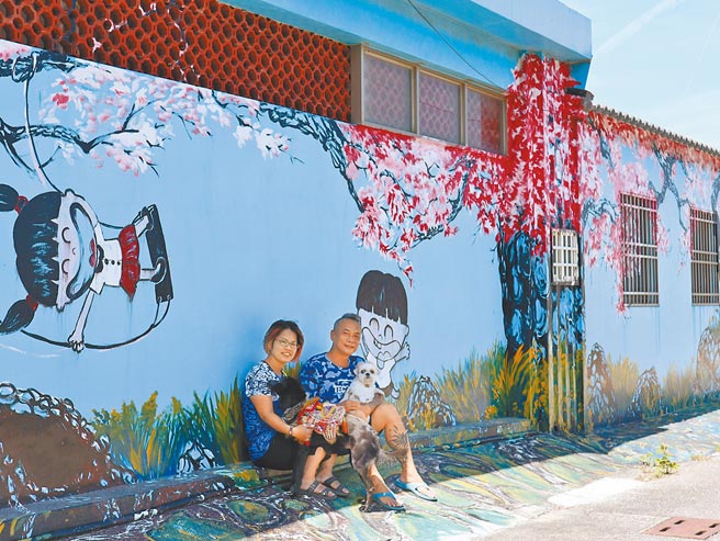 台南市北门区蚵寮里洪六宝塔外墙上的樱花彩绘作品，出自王倩玲（左）与丈夫杨逸（右）之手。（张毓翎摄）