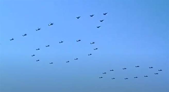 15架歼-20战机7月1日在中共建党100周年纪念的空中阅兵中，分成3支V型编队飞行，图为在先前的彩排里，其中有5架在直升机排成的100字样前编队飞行。（网路）