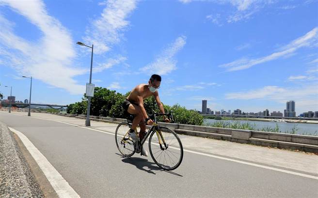 中央气象局表示，1日太平洋高压势力增强，天气晴到多云，台北局部地区有36度以上高温，白天紫外线指数容易达过量或危险级，一位民眾裸着上半身在河滨公园骑乘自行车。（张铠乙摄）
