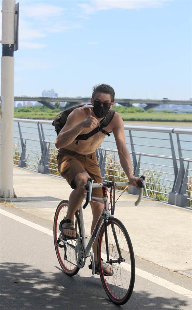 中央气象局表示，1日太平洋高压势力增强，天气晴到多云，台北局部地区有36度以上高温，白天紫外线指数容易达过量或危险级，一位民眾裸着上半身在河滨公园骑乘自行车。（张铠乙摄）
