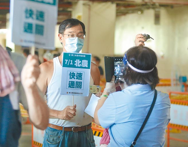 北市府持續執行批發市場大規模PCR篩檢專案，圖為工作人員在受檢人員PCR篩檢過後拍照造冊，並將使用新的PCR陰性報告入場。（粘耿豪攝）