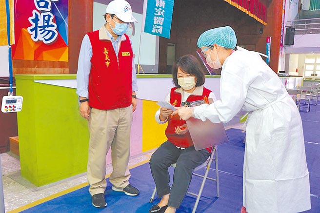 嘉義市長黃敏惠（中）視察設於北興國中的疫苗接種站，演示接種前聽取醫護人員的說明。（廖素慧攝）