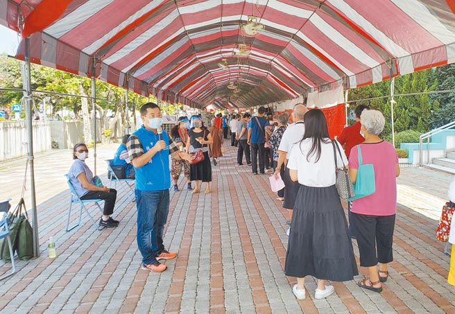 雲林縣斗六市雲林國中大禮堂快打站2日周邊擠滿人車，斗六市長林聖爵（左）持大聲公宣導說明。（周麗蘭攝）