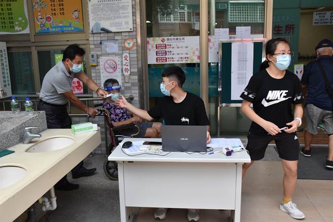 头份市卫生所主任徐春仕（左）周日加班替长者打疫苗，还带着家中3名子女前来协助接待长辈接种。（谢明俊摄）