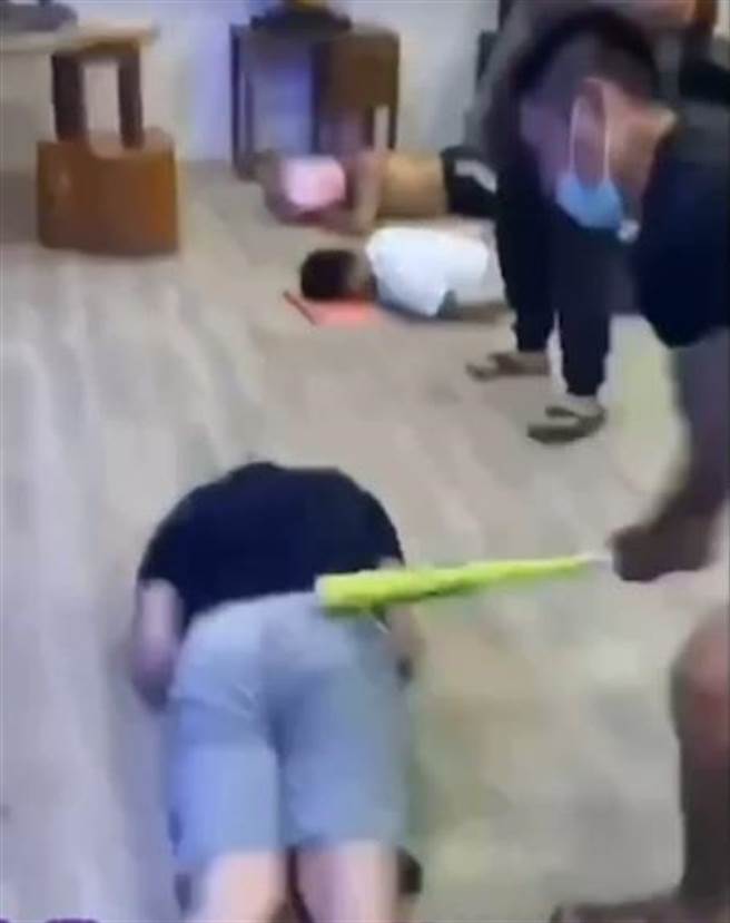 影片中1名短裤男，双手遭绑，躺在地上屁股被人持球棒狂打。（摘自黑色豪门企业）