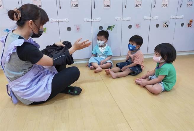 高市府推出防疫人员幼儿照顾补贴，减轻民眾压力。图为托育人员教导幼儿穿衣服。（高雄市社会局提供／林瑞益高雄传真）